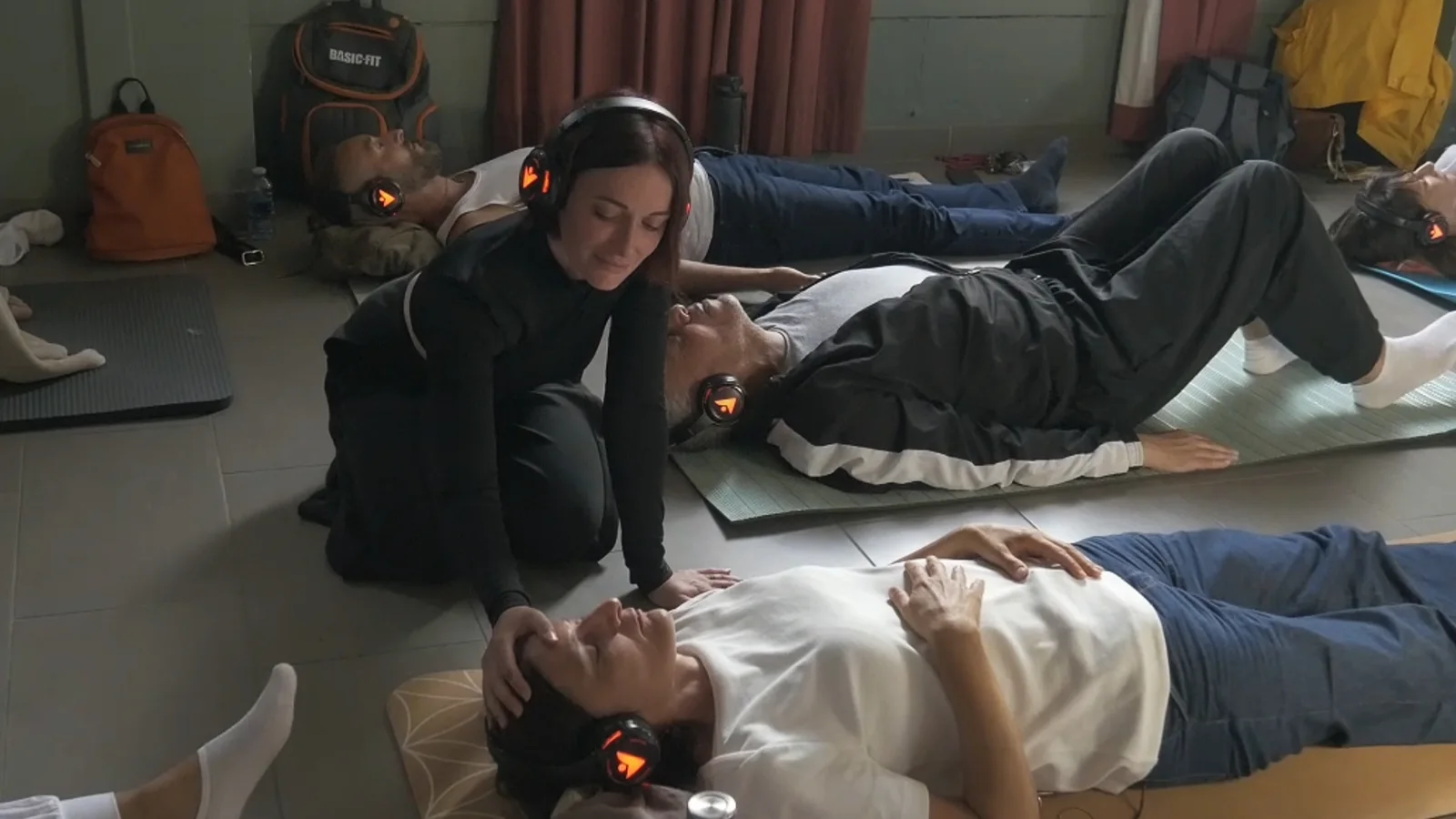 Une facilitatrice accompagne des participants allongés pendant la pratique
